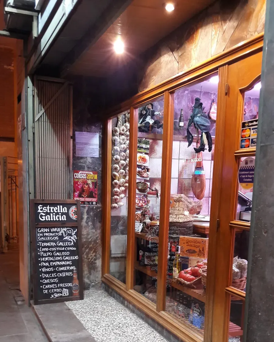 Escaparate de Casa a Pedra con la pizarra de la puerta: ternera gallega, pulpo, quesos, empanadas y dulces caseros